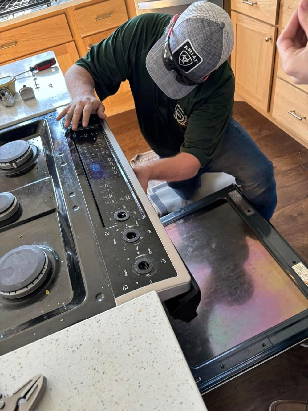Technician repairing a kitchen gas stove in a modern home.