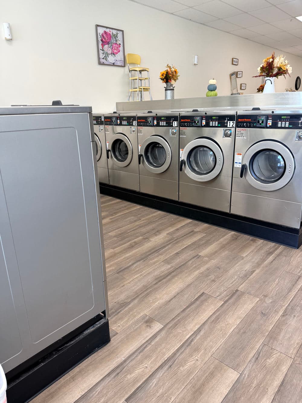 Modern laundromat with silver washing machines and a spacious, clean interior.