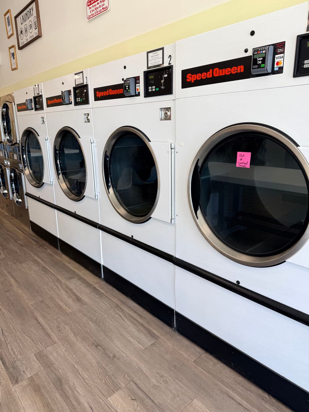 Row of Speed Queen dryers in a laundromat with modern design and clear glass doors.